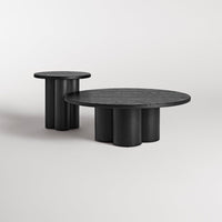 Black round and cylindrical coffee tables with a smooth textured finish, showcasing modern minimalist design.