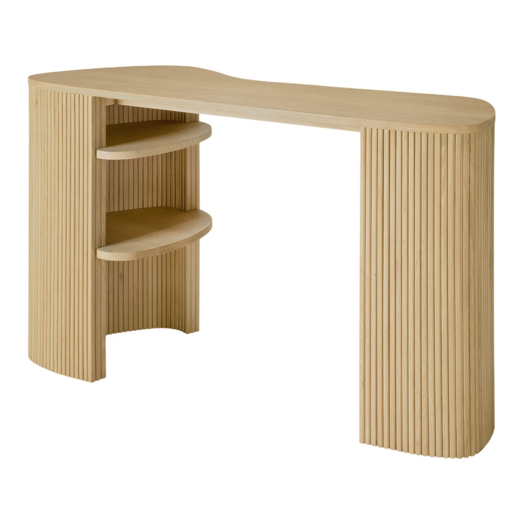 Light natural wood desk with vertical ribbed pattern and curved edges, featuring two open shelves for storage.