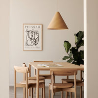 Wooden dining table and chairs with natural tones, set against soft beige walls and a graphic black and white artwork.