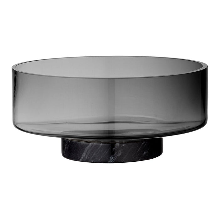 Smoky gray glass bowl with a sleek black marble base, featuring a modern, minimalist design.