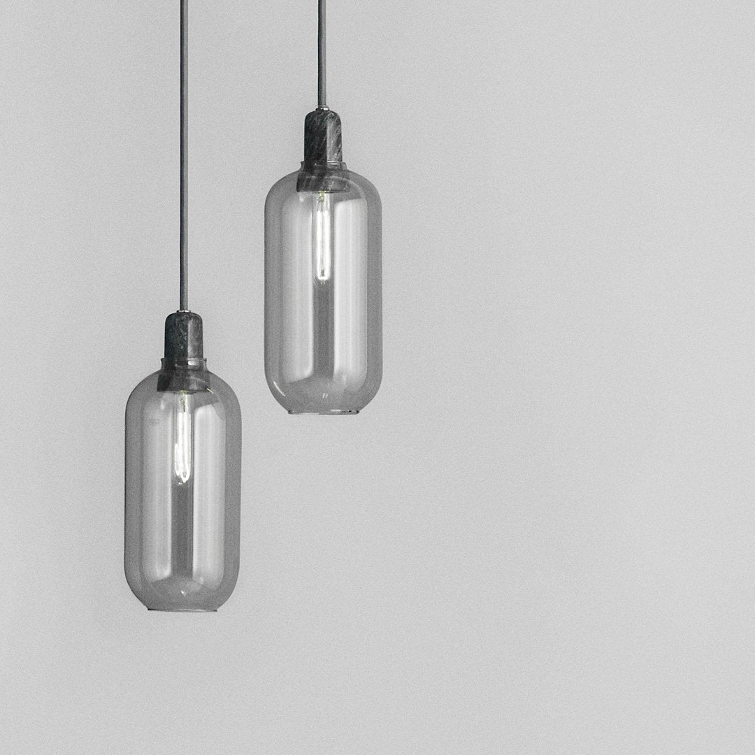 Gray glass pendant lights with a sleek, minimalist design and contrasting black fittings, ideal for modern decor.