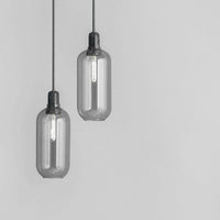 Gray glass pendant lights with a sleek, minimalist design and contrasting black fittings, ideal for modern decor.