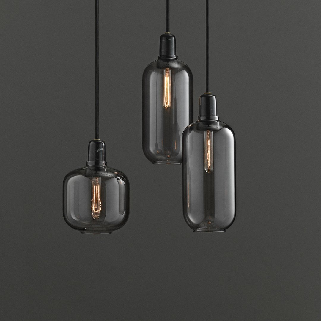 Black glass pendant lights with vintage-style bulbs, featuring sleek, modern shapes and a minimalist design.