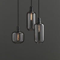 Black glass pendant lights with vintage-style bulbs, featuring sleek, modern shapes and a minimalist design.