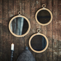 Three round mirrors with natural wood frames, featuring a mix of reflective and matte surfaces. Simple, rustic charm.