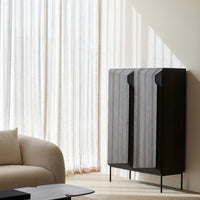 Modern cabinet featuring a sleek black finish with gray patterned accents against a light, airy backdrop.