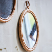 "Natural bamboo oval mirror with a smooth, reflective surface and a warm tan frame, perfect for rustic decor."