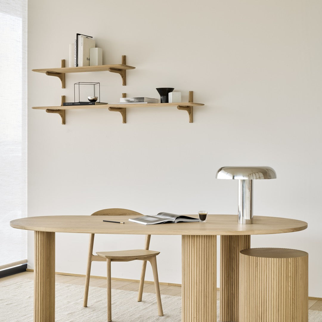 Light wood dining table with subtle striped patterns, complemented by minimalist shelves and soft neutral tones.