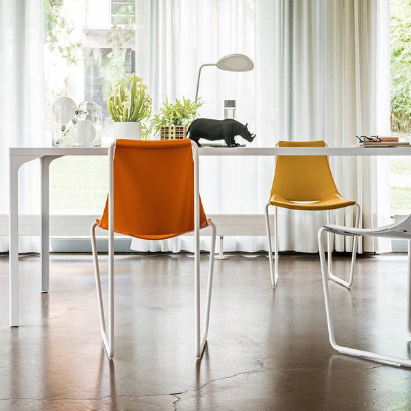 "Stylish chairs in vibrant orange and yellow with a sleek white frame, set against a bright, modern interior."