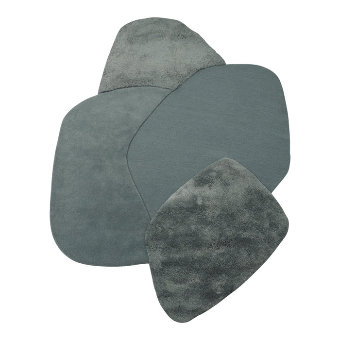 Four soft, textured rugs in shades of muted teal and gray, featuring unique organic shapes and patterns.
