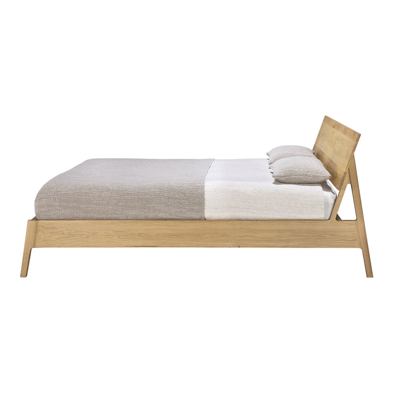 Natural wood bed frame featuring a minimalist design with a neutral beige and light gray bedding arrangement.