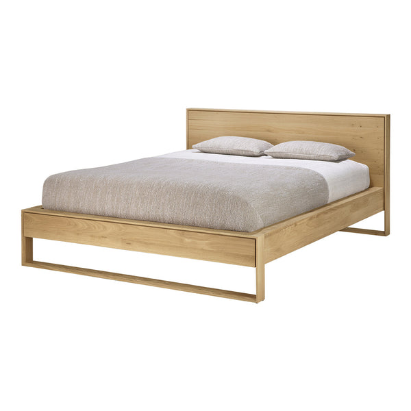 Light oak bed frame with a minimalist design, featuring soft beige bedding and a subtle textured pattern.