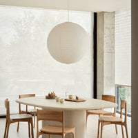 White textured pendant lamp over a light wood oval dining table with beige accents and neutral backgrounds.