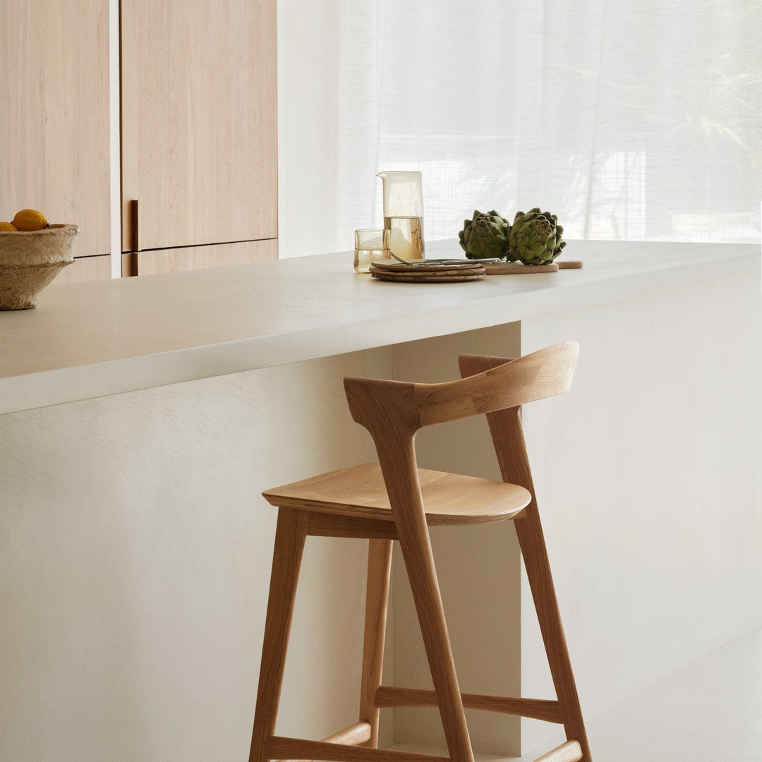 Natural wood bar stool on a minimalist light countertop with beige and soft white tones. Elegant and modern design.