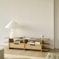 Light wood shelf unit with a natural finish, complemented by a textured white lamp and subtle beige accents.