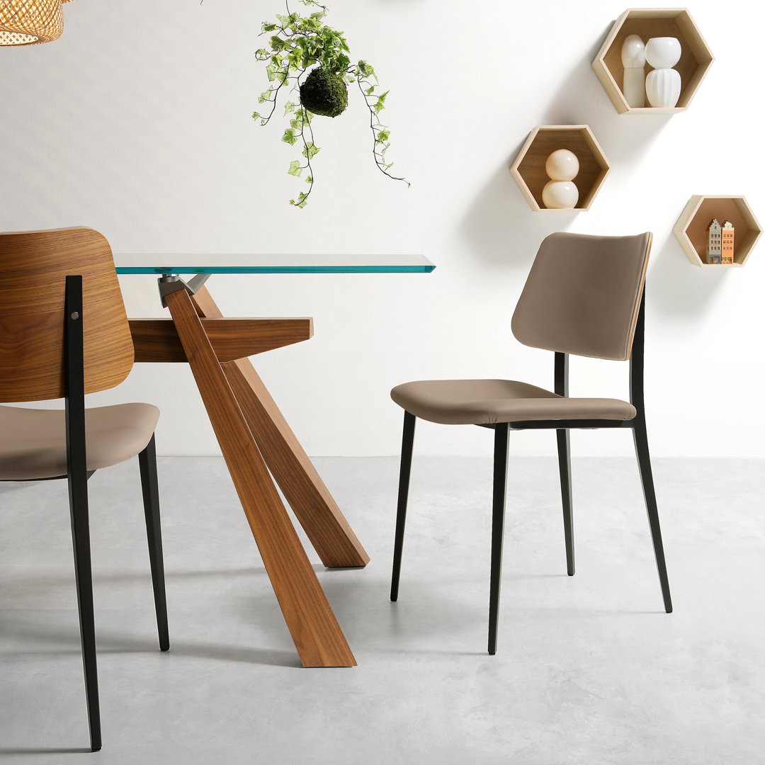 Neutral beige dining chair with sleek black legs, paired with a modern wooden table and minimalist decor elements.
