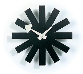 Black and white starburst wall clock with geometric rays and contrasting hands, modern minimalist design.