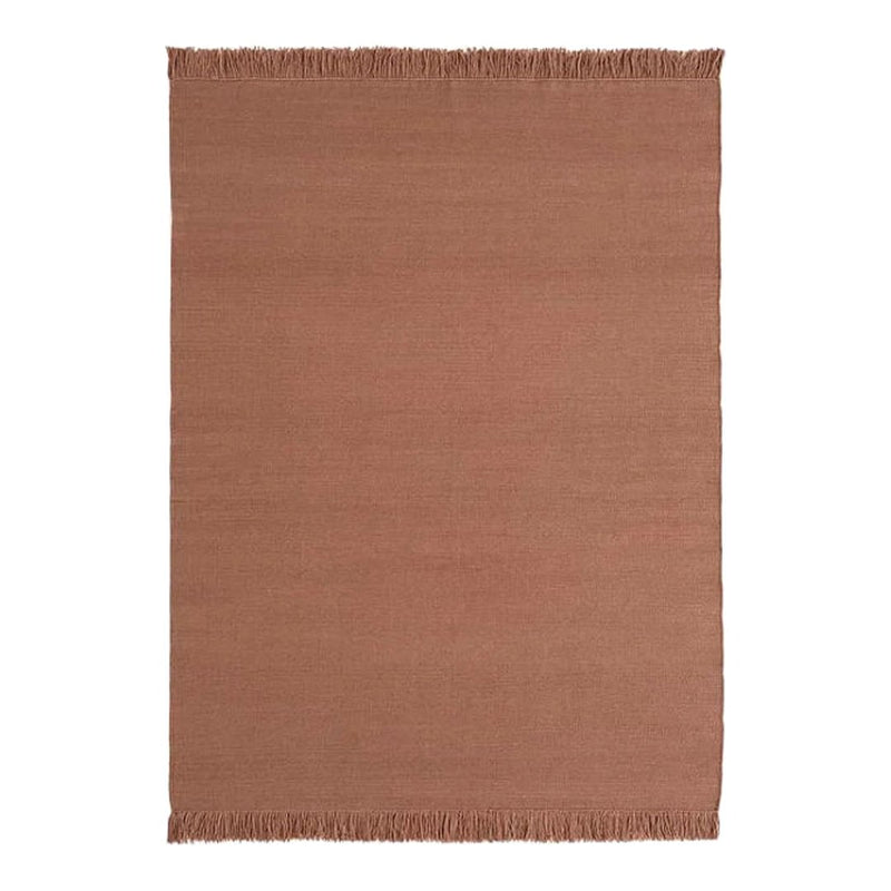 Rust-colored woven rug with a subtle texture and fringed edges, perfect for adding warmth to any space.