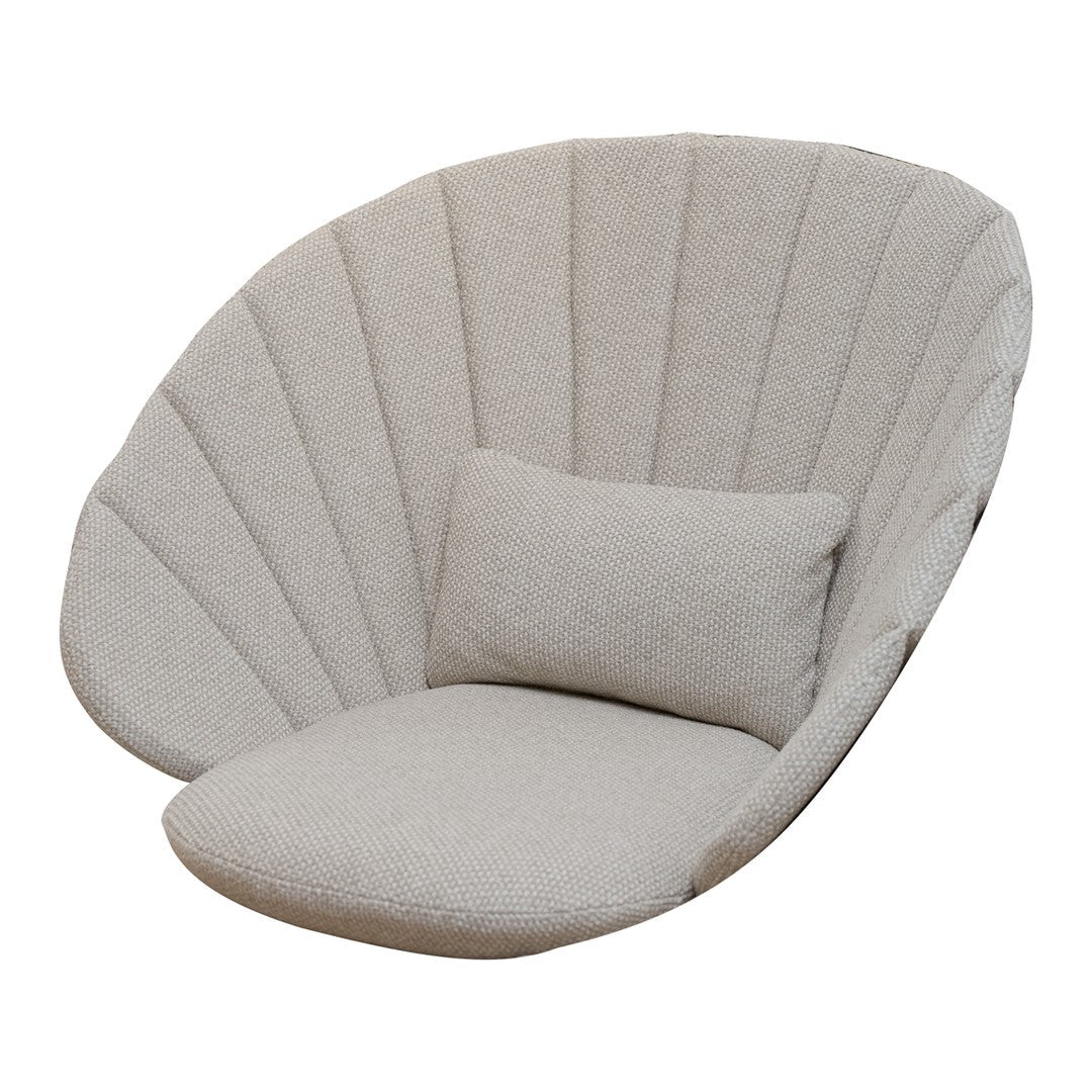 Light beige shell-shaped chair with vertical ribbed pattern and a matching plush cushion for added comfort.