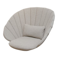 Light beige shell-shaped chair with vertical ribbed pattern and a matching plush cushion for added comfort.