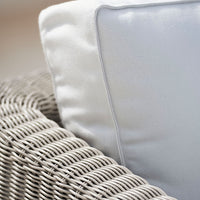Light gray woven wicker chair with a white pillow featuring a subtle gray border.