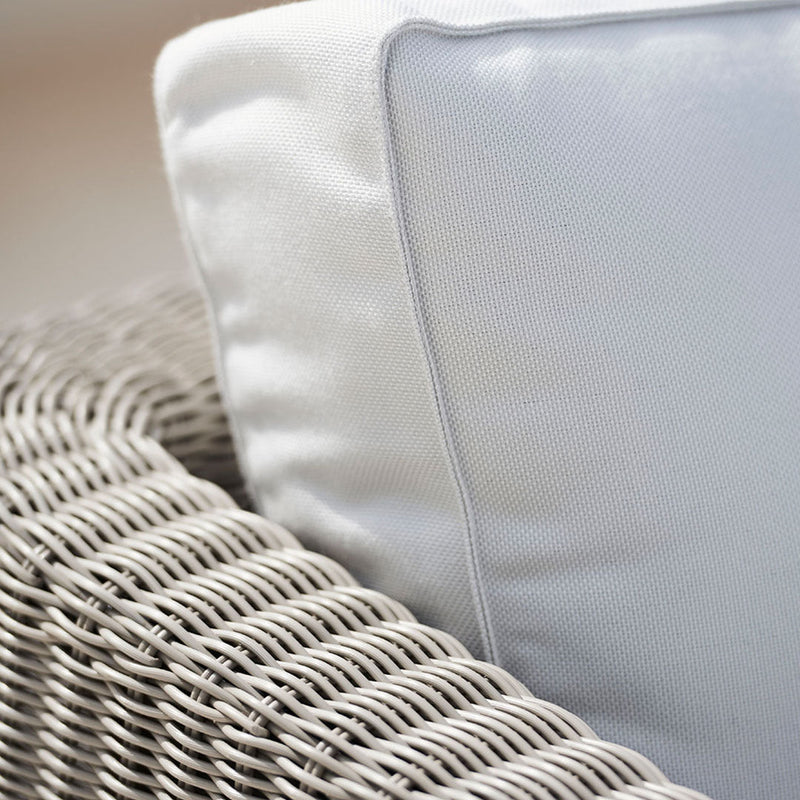 Light gray woven wicker chair with a white pillow featuring a subtle gray border.