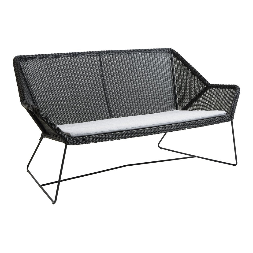 Black wicker loveseat with white cushion, featuring a modern geometric pattern and sleek metal legs.