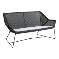 Black wicker loveseat with white cushion, featuring a modern geometric pattern and sleek metal legs.