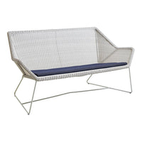White woven loveseat with a deep navy cushion, featuring a modern geometric design and sleek metal legs.