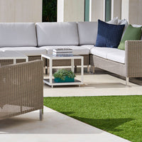 Modern outdoor seating in neutral tones with blue and green accent pillows, woven texture, and clean white table.