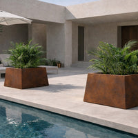 Rusty brown rectangular planters with lush green plants, set against a minimalist stone patio and blue pool.