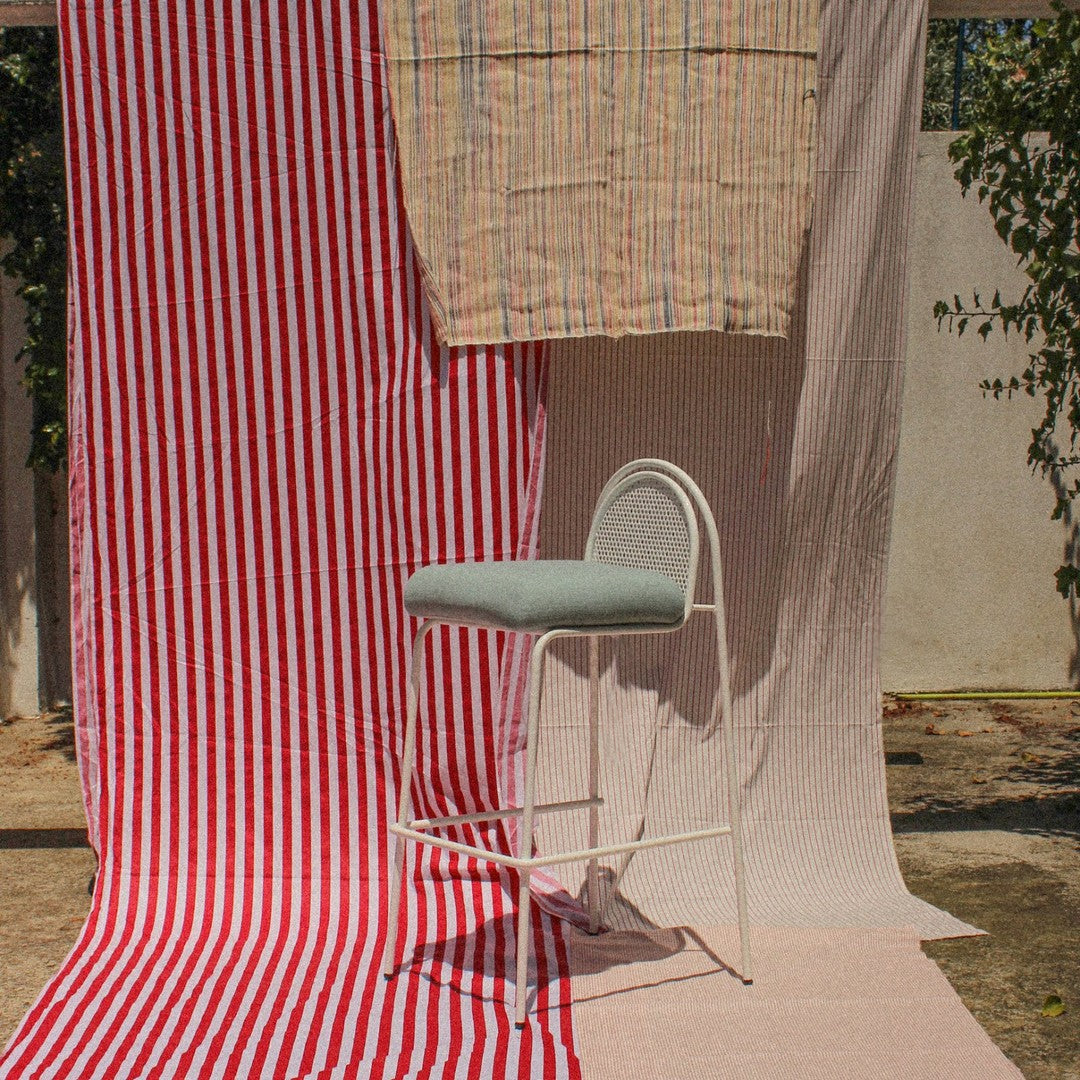 Red and white striped fabric with a pastel-patterned backdrop and a light blue upholstered chair in the foreground.