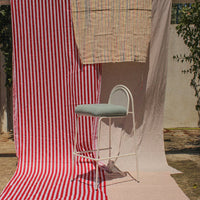 Red and white striped fabric with a pastel-patterned backdrop and a light blue upholstered chair in the foreground.