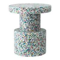 Colorful speckled table featuring a round top and cylindrical base in bright hues of blue, red, green, and white.