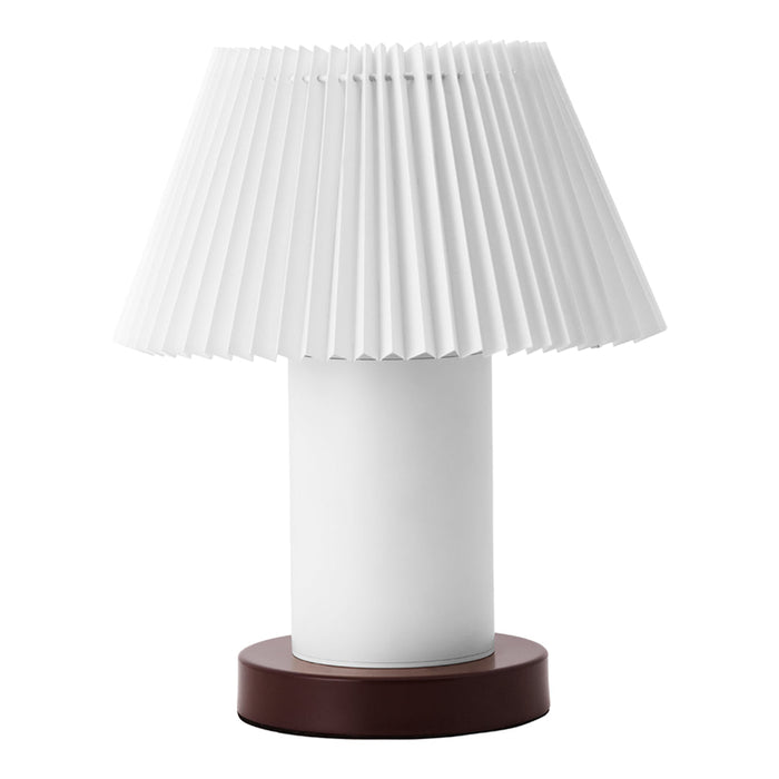 White pleated lampshade on a cylindrical white base with a dark brown circular bottom. Elegant and modern design.