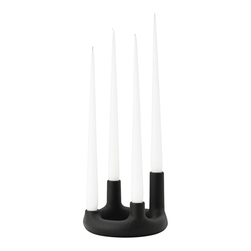 Black candle holder with four long white candles, creating a modern, minimalist design.