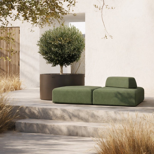 Modern green outdoor couch with soft, minimalist design, paired with a sleek dark planter against a neutral backdrop.