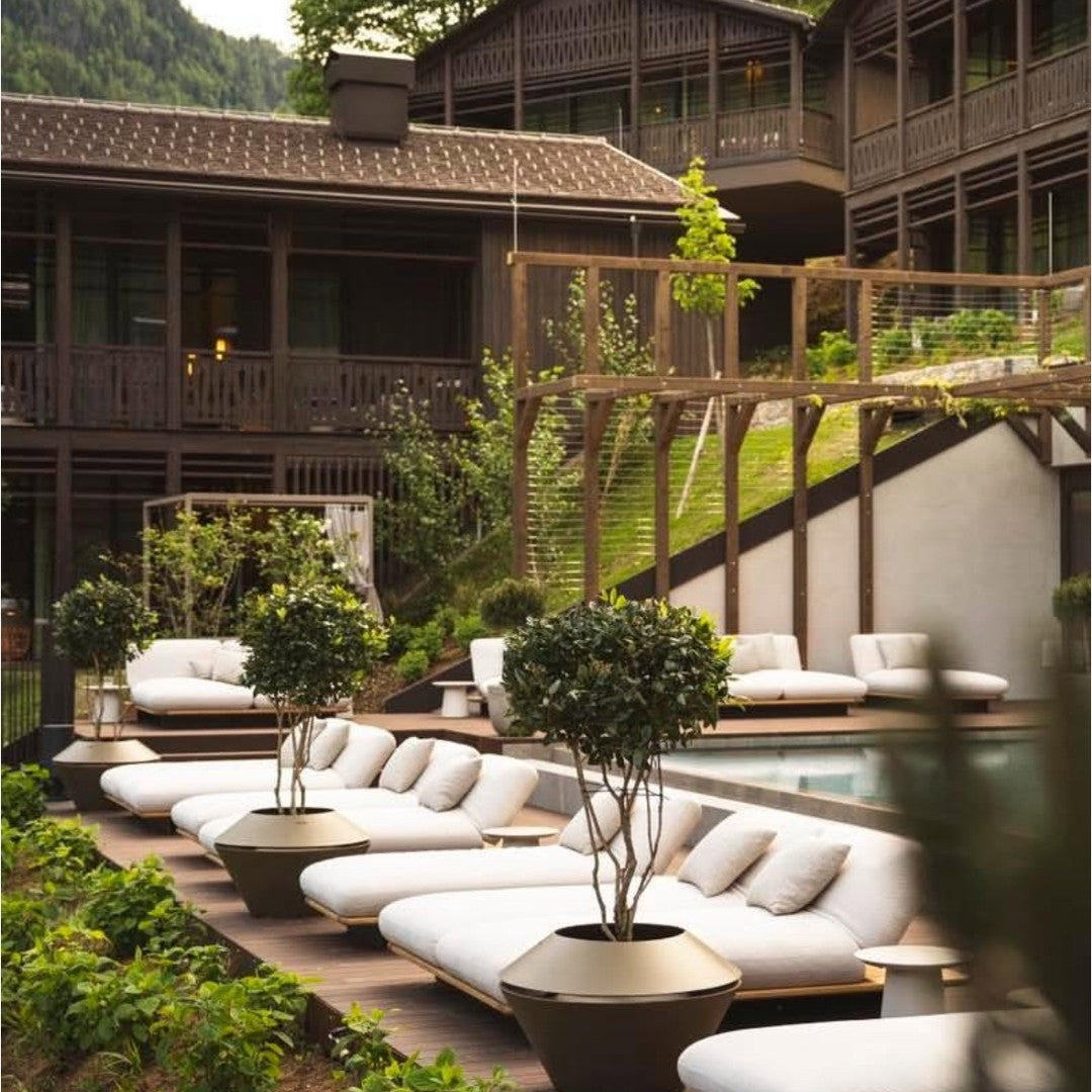 Stylish white lounge chairs with green foliage and wooden accents, set in a serene, natural landscape.
