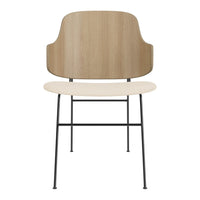 Minimalist chair featuring a light wood backrest, cream seat, and sleek black metal legs. Modern design with earthy tones.