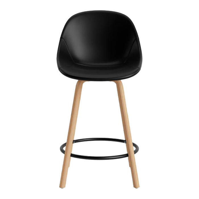 Black padded stool with natural wood legs and a sleek black metal footrest, showcasing a modern minimalistic design.