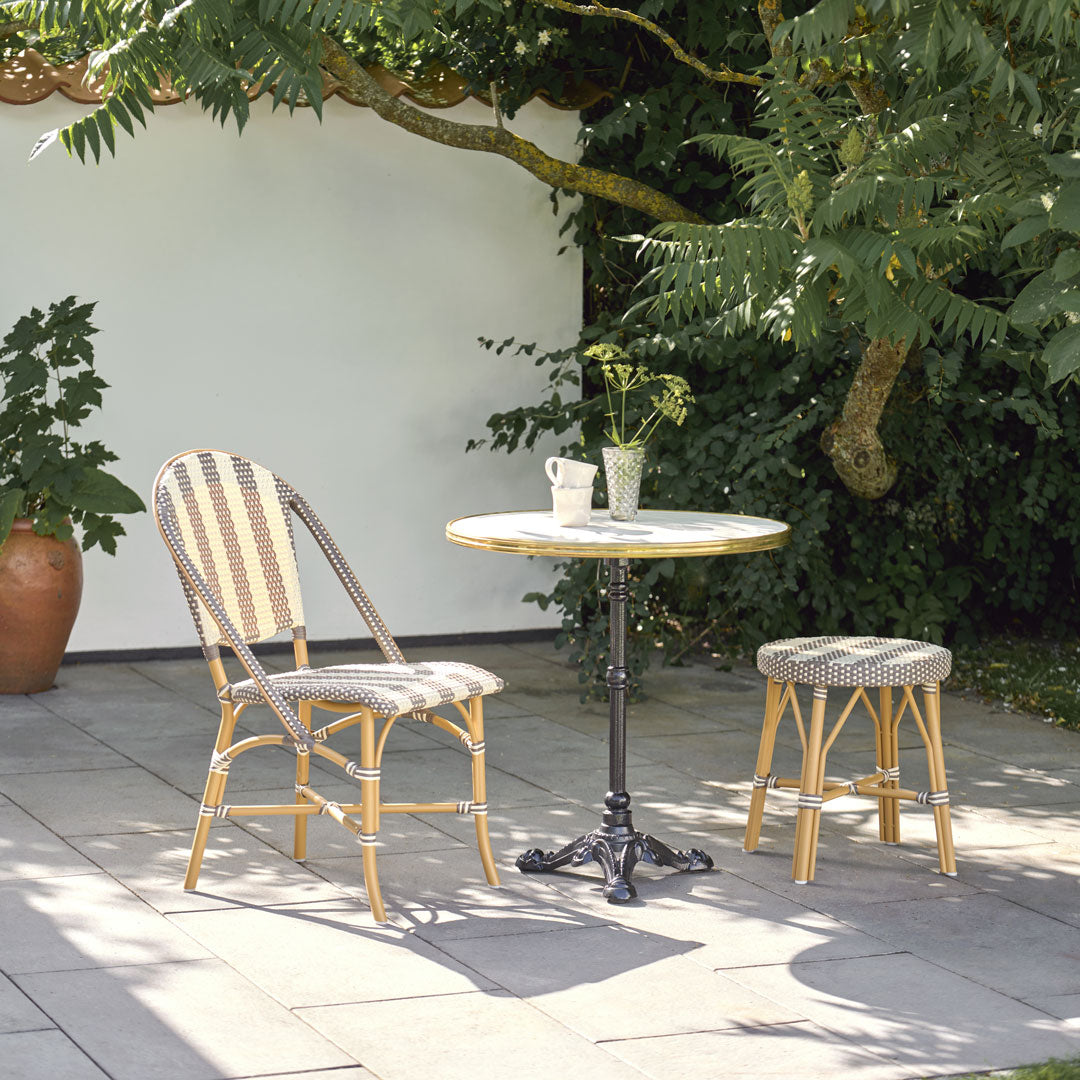 "Natural rattan chair and stool with grey and white patterns, paired with a round marble-top table with black metal base."