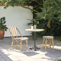 "Natural rattan chair and stool with grey and white patterns, paired with a round marble-top table with black metal base."