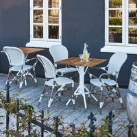 White and beige bistro chairs with wooden table, set against a dark gray wall, ideal for outdoor dining.