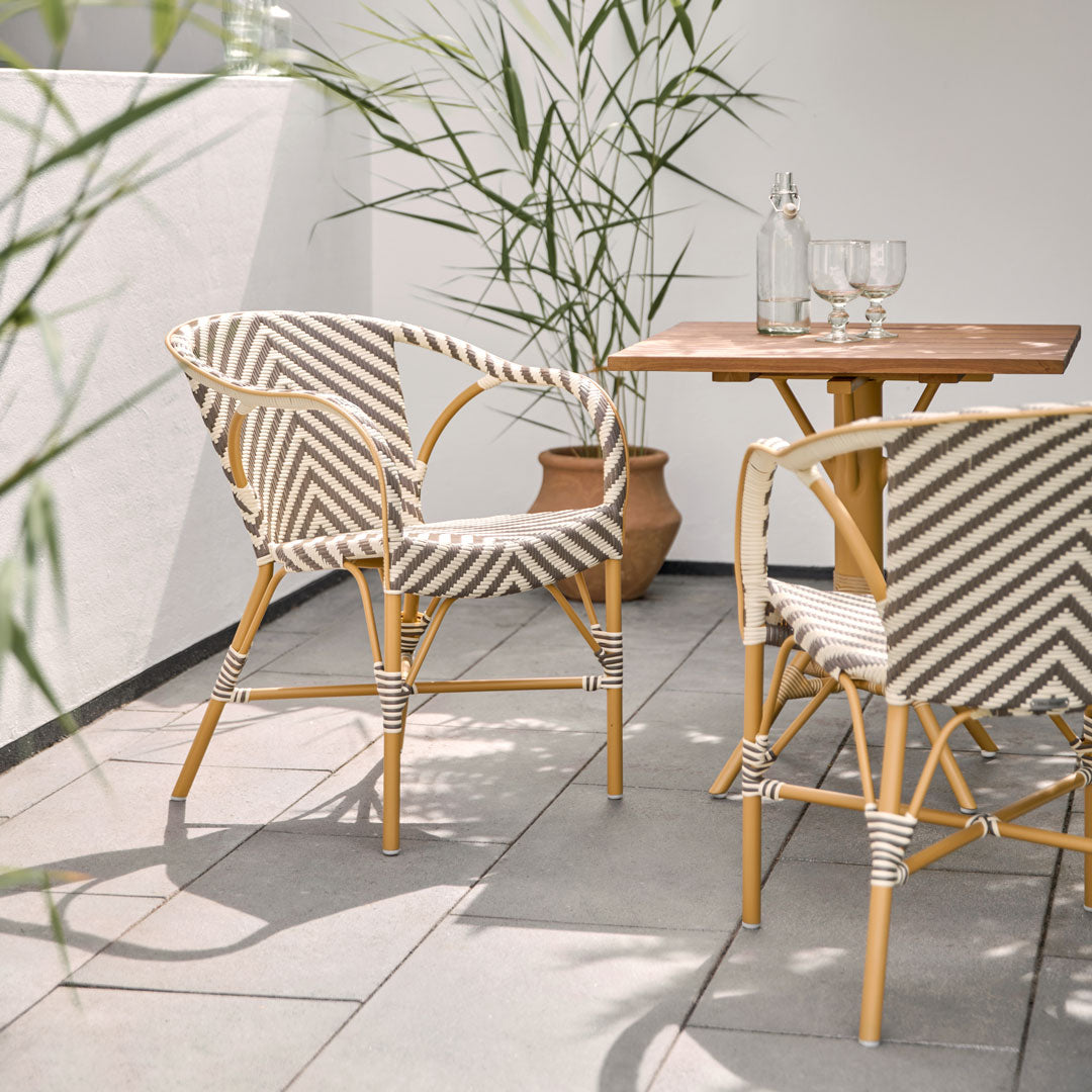 Striped beige and white patterned chairs with natural wood table in a modern outdoor setting.