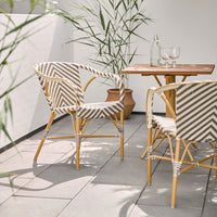 Striped beige and white patterned chairs with natural wood table in a modern outdoor setting.