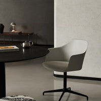Stylish gray armchair with smooth curves against a minimalist black table and neutral-toned backdrop.
