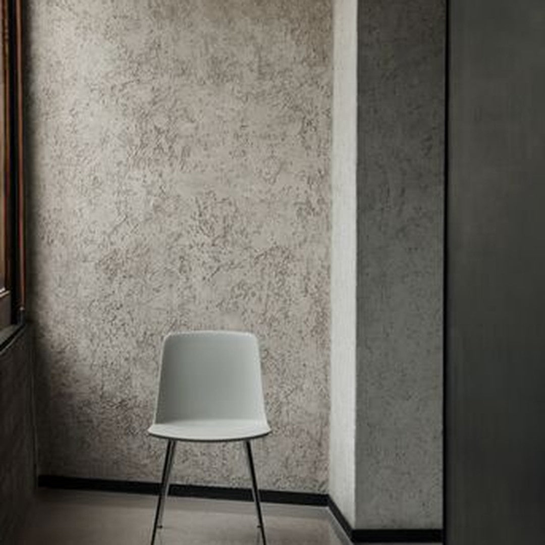 Light gray modern chair against a textured gray wall in a minimalist setting. Stylish and versatile decor piece.