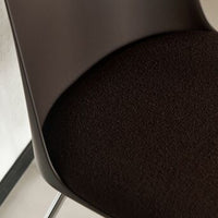 Dark brown textured fabric seat with a smooth black plastic shell and chrome legs. Modern design with minimalist appeal.