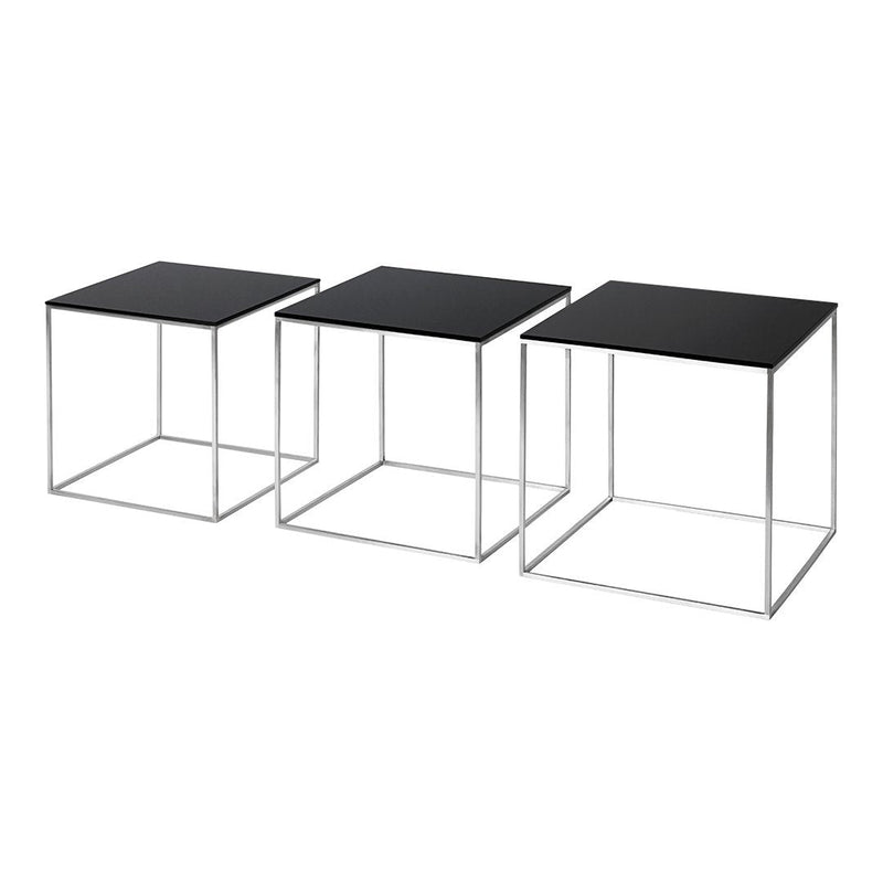 Set of three modern side tables with sleek black tops and minimalistic silver metal frames. Geometric design accents.