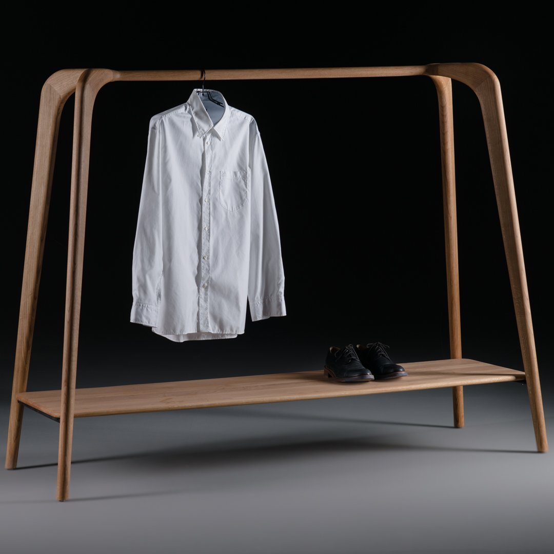 White button-up shirt on a minimalist natural wood clothing rack with a sleek black base and stylish black shoes.